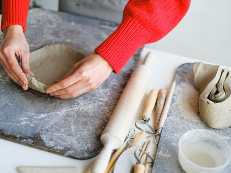 A closeup of a woman moulding handmade pottery with her hands.